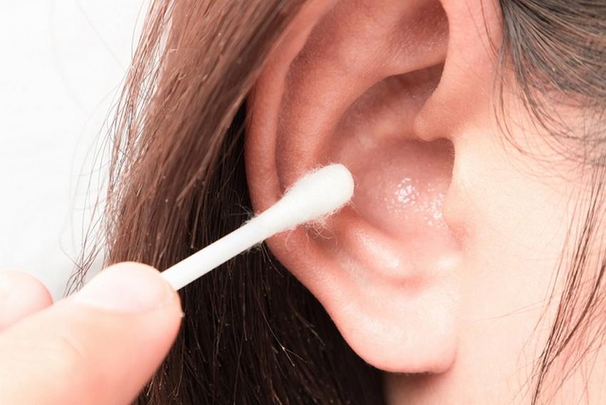 Closeup woman cleaning ear with cotton bud health care concept